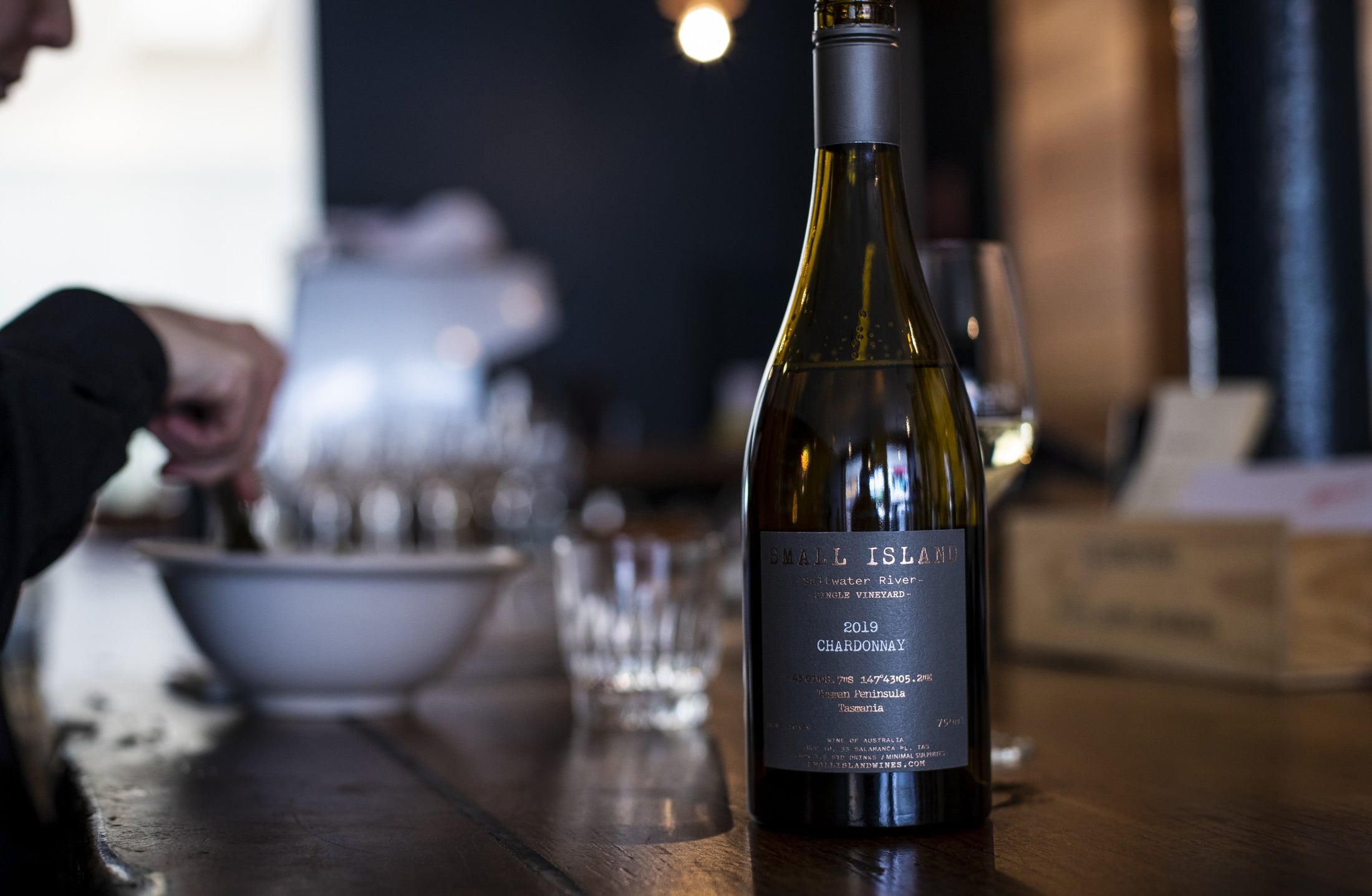 A 2019 Saltwater River Single Vineyard Chardonnay on a bar, glasses being set out behind it